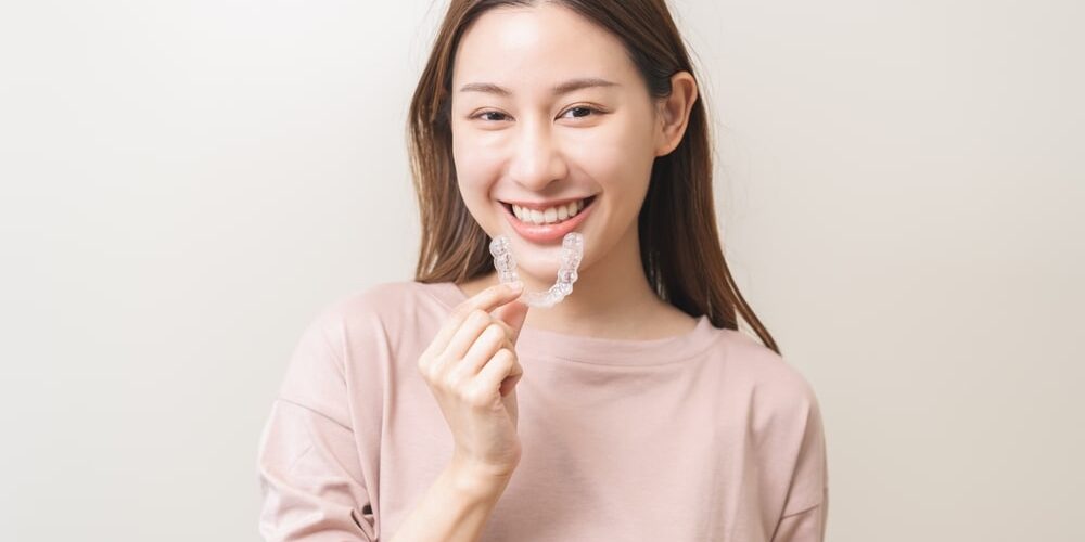 smiling woman holding up a invisalign product