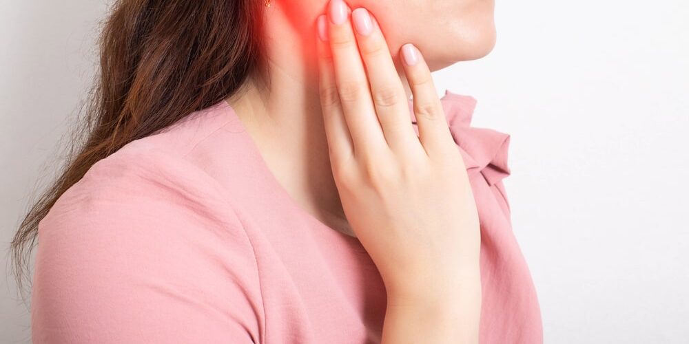 girl holding her hand on the lower jaw of the tooth, which has an inflamed tooth nerve, dental abscess.